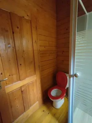 a bathroom with a red toilet in a wooden room at chalets bois 150m de la plage in Olmeto