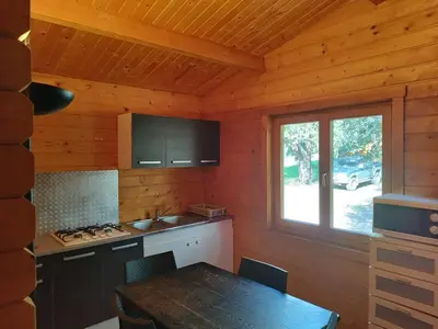a kitchen with a table and a window in a cabin at chalets bois 150m de la plage in Olmeto
