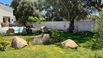 a yard with rocks in the grass next to a fence at Chambre d'hôtes Casa Tib in Prunelli-di-Fiumorbo