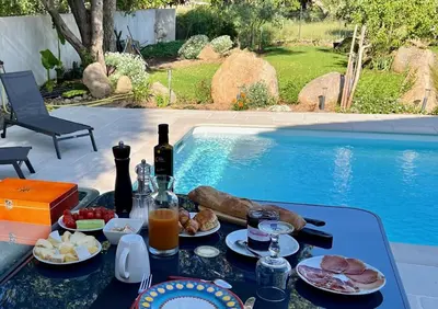a table with food and drinks next to a swimming pool at Chambre d'hôtes Casa Tib in Prunelli-di-Fiumorbo