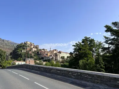 a road with houses on a hill in the distance at Joli appartement F2 centre ville de Corte in Corte