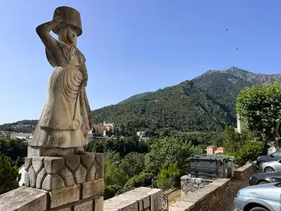 a statue of a woman standing on a wall with mountains in the background at Joli appartement F2 centre ville de Corte in Corte