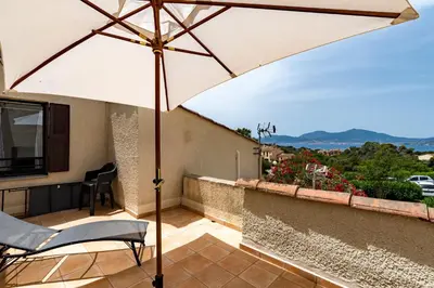 a patio with an umbrella and chairs on a balcony at Le Paesolu in Grosseto-Prugna