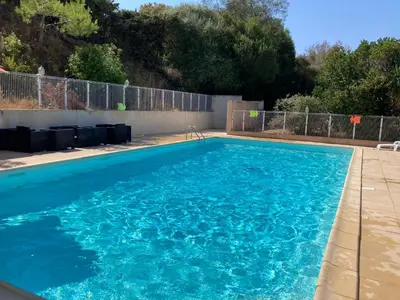 a swimming pool with blue water in a yard at Le Paesolu in Grosseto-Prugna