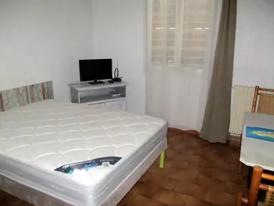 a bedroom with a white bed and a television at T2 Casamozza Sud de Bastia climatisé in Monte