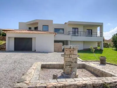 a large house with a garage in front of it at Appartement tranquille en bas de villa in Afa