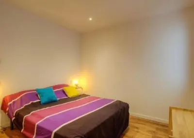 a bedroom with a bed with colorful pillows on it at Appartement tranquille en bas de villa in Afa