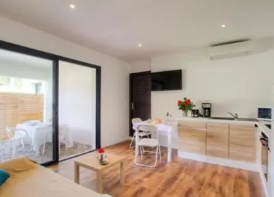 a living room with a kitchen and a dining room at Appartement tranquille en bas de villa in Afa