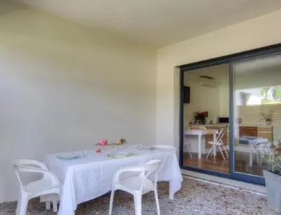 a dining room with a white table and chairs at Appartement tranquille en bas de villa in Afa