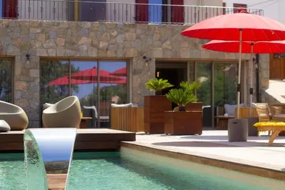 a pool with tables and chairs and red umbrellas at Hôtel Casale Olmia in Moncale