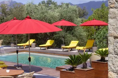 a pool with yellow chairs and red umbrellas at Hôtel Casale Olmia in Moncale