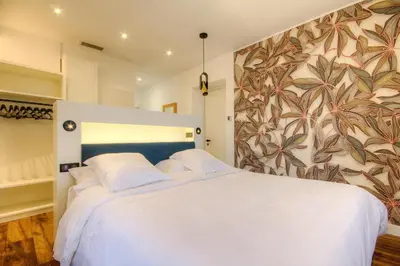 a bedroom with a white bed with a floral wall at Hôtel Casale Olmia in Moncale