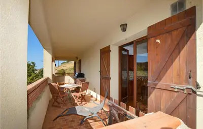 a balcony with a wooden door and a table and chairs at Cozy Apartment In Porticcio With Wifi in Porticcio