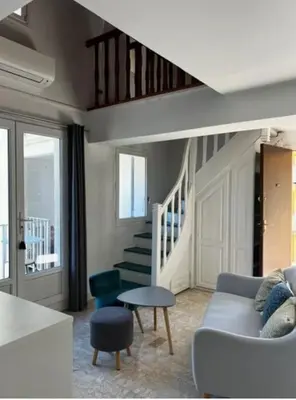 a living room with a couch and a staircase at Appartement duplex plein sud sur le port de Bonifacio in Bonifacio