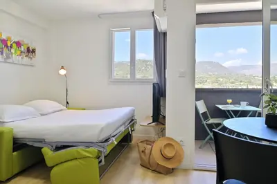 a room with a bed and a table and a window at Résidence Easy Lodge in Ajaccio