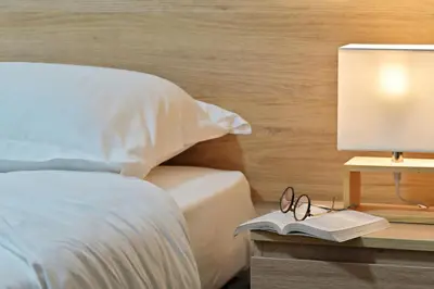 a bed with a table with a lamp and a book at Résidence Easy Lodge in Ajaccio