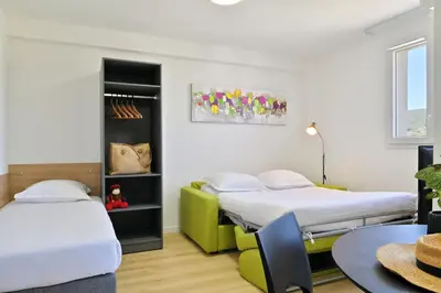 a room with two beds and a table at Résidence Easy Lodge in Ajaccio