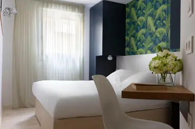 a bedroom with a white bed and a table with a chair at Hotel Alcyon in Porto-Vecchio