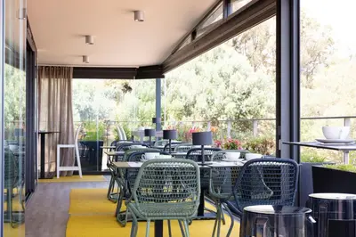 a row of tables and chairs in a restaurant with windows at Hotel Alcyon in Porto-Vecchio