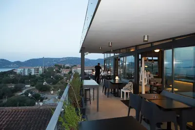 a balcony of a restaurant with tables and chairs at Hotel Alcyon in Porto-Vecchio