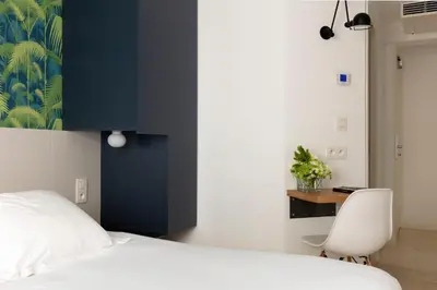 a bedroom with a white bed and a white chair at Hotel Alcyon in Porto-Vecchio