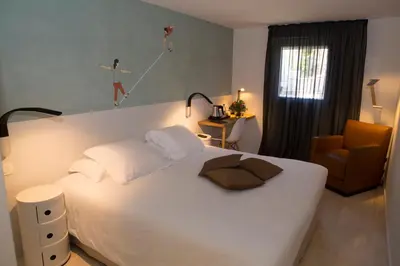 a bedroom with a bed with a person jumping on the wall at Hotel Alcyon in Porto-Vecchio