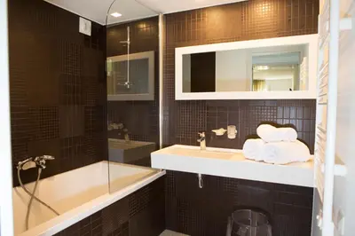 a bathroom with a sink and a mirror and a tub at Hotel Alcyon in Porto-Vecchio