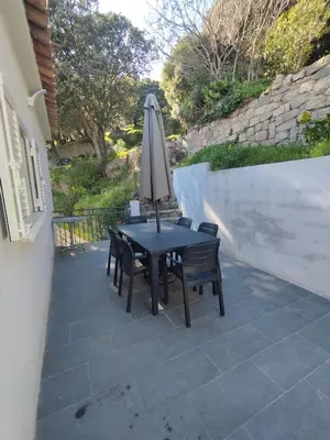 a table with an umbrella and chairs on a patio at Olmeto 3 pièces in Olmeto