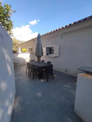a patio with a table and chairs and an umbrella at Olmeto 3 pièces in Olmeto