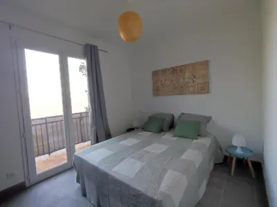a bedroom with a bed and a large window at Olmeto 3 pièces in Olmeto