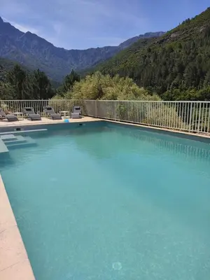 a large swimming pool with chairs and mountains in the background at Les bergeries de Montestremo in Manso