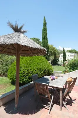 a table and chairs under an umbrella on a patio at Résidence Domaine De Caranella in Porto-Vecchio