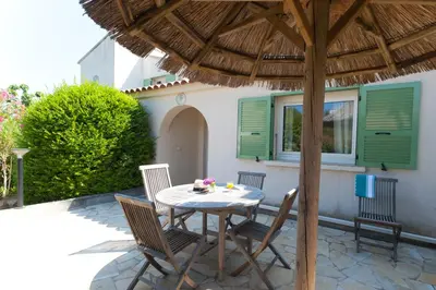 a table and chairs under an umbrella on a patio at Résidence Domaine De Caranella in Porto-Vecchio