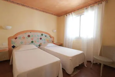 a bedroom with two beds and a window and a chair at Résidence Domaine De Caranella in Porto-Vecchio