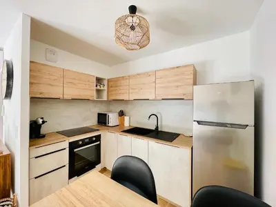 a kitchen with wooden cabinets and a stainless steel refrigerator at Ajaccio T2 grand standing neuf - centre ville et plages - 4 personnes - parking privé in Ajaccio