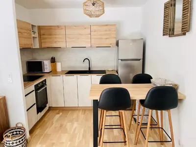 a kitchen with a wooden table and black stools at Ajaccio T2 grand standing neuf - centre ville et plages - 4 personnes - parking privé in Ajaccio