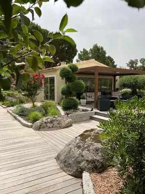a garden with a wooden deck and a house at Les Jardins De Santa Giulia - Charmante chambre dhte in Porto-Vecchio