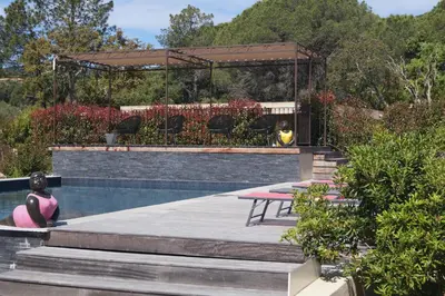 a woman sitting next to a swimming pool with a gazebo at Les Jardins De Santa Giulia - Charmante chambre dhte in Porto-Vecchio