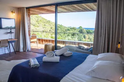 a bedroom with a bed with towels and a large window at Villa Santa Lucia Di Fautea in Sainte-Lucie de Porto-Vecchio