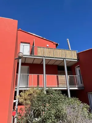 a red building with a balcony on the side of it at Chez Jeff Lucchini in Lecci