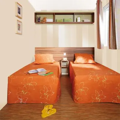 two beds in a room with orange sheets at Résidence Santa in Ghisonaccia