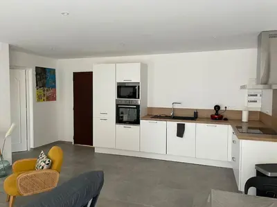 a kitchen with white cabinets and a yellow chair at Le Pélican T2 Magnifique in Ajaccio