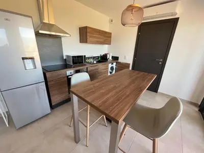 a kitchen with a wooden table and a refrigerator at T1 proche aéroport et plage in Ajaccio