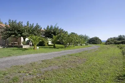 a gravel road with trees and a house at Residence Scopa Marina in Poggio-Mezzana