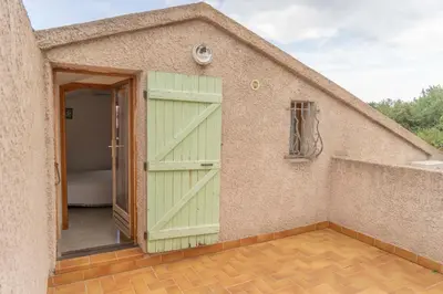 a small house with a green door and a balcony at Residence Scopa Marina in Poggio-Mezzana