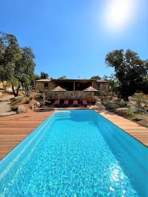 a swimming pool with a wooden deck and a house at Casetta Tinuta in Sainte-Lucie de Porto-Vecchio
