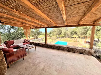 an outdoor patio with a wooden roof and a pool at Casetta Tinuta in Sainte-Lucie de Porto-Vecchio