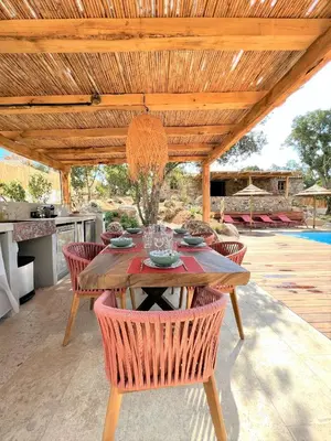 a wooden table and chairs under a wooden pergola at Casetta Tinuta in Sainte-Lucie de Porto-Vecchio