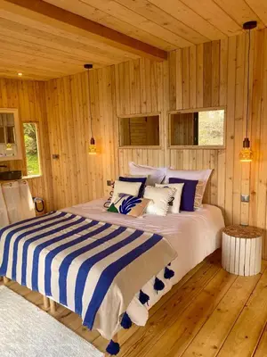 a large bed in a room with wooden walls at LES CABANES DE LUTINA in Poggio-Marinaccio