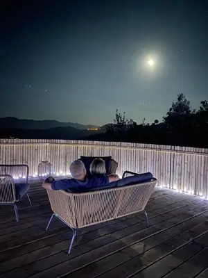 a man and a woman sitting on a bench on a deck at LES CABANES DE LUTINA in Poggio-Marinaccio
